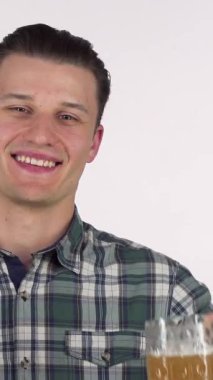 Yakışıklı genç bir adam gururla elinde köpüklü bir bira bardağıyla sizi şenlikli ruha davet eden cazip bir çubuk krakerle eşlik ederken neşe saçıyor. Canlı gülüşü ve şık ekose gömleği hayat dolu atmosferi canlandırıyor. Kutlamak için mükemmel.