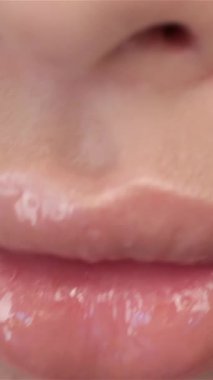 Bu büyüleyici makro görüntü, soluk pembe parlak dudakların büyüleyici cazibesini ve yumuşak stüdyo ışıklarının altında hafifçe parıldamasını sergiliyor. Odak, Asyalı bir kadının sakin, kapalı gözüne, pırıl pırıl bir güzelliğe ve sakin bir atmosfere kayıyor.