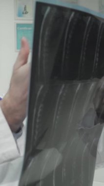 Parlak ve davetkar bir klinikte, kendini işine adamış beyaz önlüklü bir doktor, X-ray sonuçlarını büyük bir ilgiyle dinleyen genç bir kadına tutkuyla açıklar. Arka plandaki yumuşak ışıklandırma ve tıbbi çizelgeler sıcak bir bakım atmosferi yaratıyor.