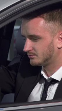 Kendine güvenen genç bir işadamı, şık ve modern bir arabada kameraya içten bir gülümsemeyle otururken başarıya ışık saçar. Bu büyüleyici görüntü lüks ve hırsı somutlaştırıyor, izleyicileri lüks otomotiv dünyasında kendi yolculuklarını düşünmeye davet ediyor.