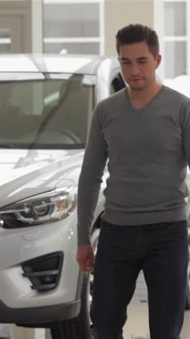 Modadan anlayan genç bir adam, modern bir otomobil galerisinde geziyor. Model arabaların göz kamaştırıcı gösterisinden büyüleniyor. Parlak, pırıl pırıl çevre, bir sonraki heyecan verici alımını tasarlayan dost canlısı bir satıcıyla ilişki kurarken heyecan saçıyor.