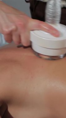 Uzman bir masör, yüksek teknolojili bir masaj aletini bir kadının kürek kemiğinin üzerinden ustalıkla geçirir ve onu sakin bir atmosferle sarar. Yakın çekim, aletin rahatlatıcı, dairesel hareketlerini yakalar, kadınların pürüzsüz cildini ön plana çıkarır ve