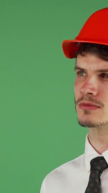 Yakışıklı bir genç adam portresi, bakımlı sakallı, parlak turuncu bir şapka ve parlak beyaz bir gömlek giymiş, uzaklığa bakarken düşüncelere dalmış. Onun düşünceli yüz ifadesi, canlı yeşil bir kromakey arka plan karşı set