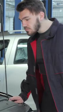 İyi bakımlı sakallı ve esmer saçlı odaklanmış genç bir tamirci canlı bir benzin istasyonunda arabanın kaputunun altındaki motoru dikkatle inceliyor. Profesyonel tulumlar giyer, İngiliz anahtarını ustalıkla kullanır, uzmanlığını somutlaştırır ve...