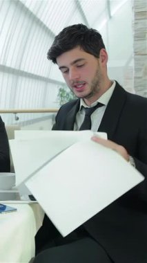 Doğal ışıkla dolu gösterişli, çağdaş bir ofiste, dört kendine güvenen işadamı, belgeler ve bir dizüstü bilgisayar üzerinde yenilikçi fikirler ve stratejiler alışverişinde bulunarak ateşli bir tartışmaya giriştiler. Arkadaşlıkları ve coşkuları heyecan verici.