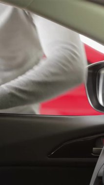 Genç bir adam modern bir aracın konforlu iç kısımlarına hevesle yaslanır, son teknoloji tasarımı ve özelliklerine hayranlıkla bakarken gözleri heyecanla parlar. Bu dinamik sahne araba alışverişinin heyecanını yakalıyor.