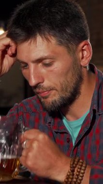 Olgun, sakallı bir adam, derin düşüncelere dalmışken, sıcak bir barda oturmuş, soğuk bir birayı kucaklıyor. Bar ışıklarının yumuşak, sıcak parıltısı yumuşak gölgeler bırakır, yalnızlık atmosferini ve yansıtıcı melankoliyi arttırır.