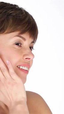 Işıl ışıl cildi parlayan orta yaşlı bir kadın yüzünü nazikçe okşar, kusursuz cildini el değmemiş beyaz bir arkaplanda gösterir. Bu büyüleyici portre güzelliği ve özgüveni temsil ediyor. Yaşlanmanın zarafetini kutluyor.