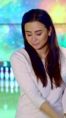 Neşeli genç Asyalı bir kadın canlı pembe bir bowling topunu tutarken heyecanla ışıldıyor, kendine güvenini yayıyor. Göz kamaştırıcı bir kozmik arkaplan karşısında bovling sahasında duruyor, oyunun heyecanını ve enerjisini somutlaştırıyor.