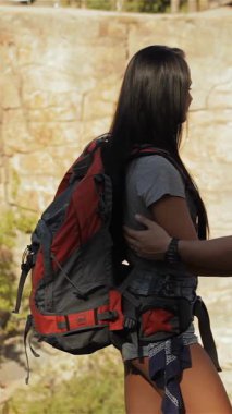 Neşeli bir çift genç yürüyüşçü yan yana duruyor, büyüleyici bir doğal manzaraya dürbünle bakıyorlar. Sakallı beyaz adam dürbünü güzel esmer kız arkadaşıyla paylaşıyor. İkisi de canlı açık hava kıyafetleri giymiş ve ışık saçıyor.