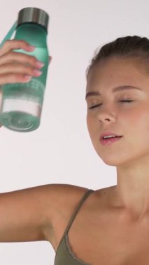 Kararlı bir sporcu kadın serinliyor, alnına serinletici bir su şişesi bastırıyor, kendine güven ve güç yayıyor. Huzurlu ifadesi, hafif bir egzersizin ardından gevşeme ve gençleşme mutluluğunu somutlaştırıyor.