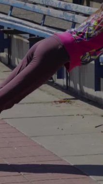 Ateşli genç bir kız tutkulu bir şekilde stadyumda jimnastik yapıyor etkileyici atletizmini ve sarsılmaz dikkatini sergiliyor. Canlı, renkli spor kıyafetleri içinde, kararlılıkla öne eğiliyor, somut güç ve adanmışlıkla.