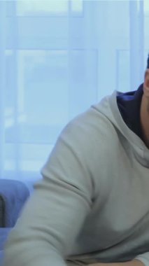 Orta yaşlı, yakışıklı, bakımlı sakallı beyaz bir adam, güneşli bir kuytuda rahat bir şekilde oturan sıcak bir fincan yeşil çayın tadını çıkarıyor. Rahatlamış tavrı ve davetkar gülüşü sıcaklığı yayıyor. Rahatlamak için mükemmel sakin bir atmosfer yaratıyor.