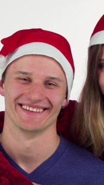 Sıcak kırmızı bir battaniyeye sarılmış neşeli bir çift, Noel Baba şapkaları giyerken samimi bir kucaklaşmayı paylaşıyor. Onların ışıldayan gülümsemeleri sevgi ve tatil ruhu yayar, Noel birlikteliğinin büyüsünü mükemmel bir şekilde yakalar.