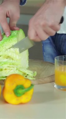 Neşeyle ışıldayan iki genç arkadaş, taze sebzelerle dolu güneşli bir mutfakta canlı yeşil ve mor lahanaları ustalıkla dilimliyorlar. Canlı sahne renkli biberler ve sulu domateslerle dolup taşar, sağlıklı bir yaşam için davetkar bir atmosfer yaratır.