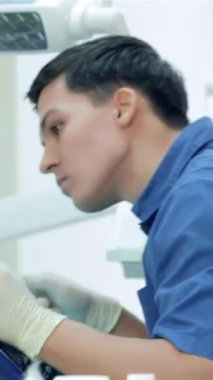 Parlak ışıkla dolu modern bir diş kliniğinde, kendini işine adamış bir diş hekimi hastanın dişlerini ustalıkla döverken, neşeli bir bayan asistan da umut verici bir onay sunuyor. Bu canlı sahne diş bakımındaki sinerji ve pozitifliği vurgular.