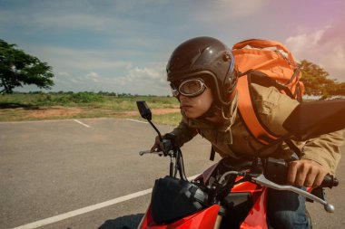 El hipster genç adam bir motosiklet üzerinde kapatın. Mutlu bir adam yönü gösterir. Motosiklet. kırmızı ve siyah motosiklet ile sırt çantası