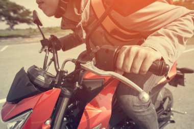 El hipster genç adam bir motosiklet üzerinde kapatın. Mutlu bir adam yönü gösterir. Motosiklet. kırmızı ve siyah motosiklet ile sırt çantası