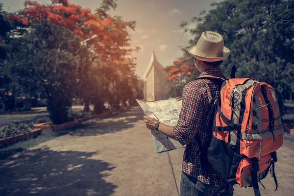 Asia young handsome man traveler with red backpack and hat enjoying a looking at map.Traveling along Asia, active lifestyle concept