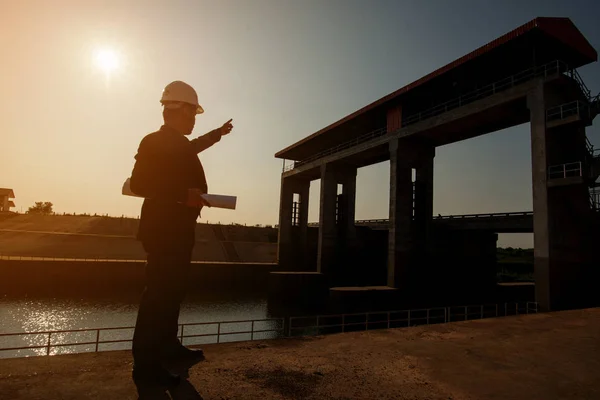 Business Industrial,People,personal and career growth, progress and potential concepts.Businessman engineer looking blueprint in a dam site.silhouette engineering working in site