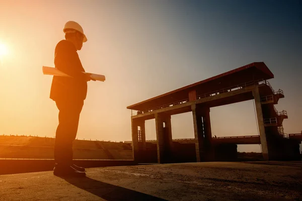 Business Industrial,People,personal and career growth, progress and potential concepts.Businessman engineer looking blueprint in a dam site.silhouette engineering working in site