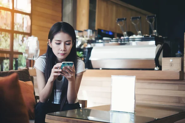 コーヒー ショップで携帯電話のディスプレイを見て幸せの美しいアジアの女性 — ストック写真