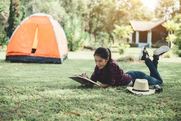 Çimlerin üzerinde kitap okuyan güzel kız.