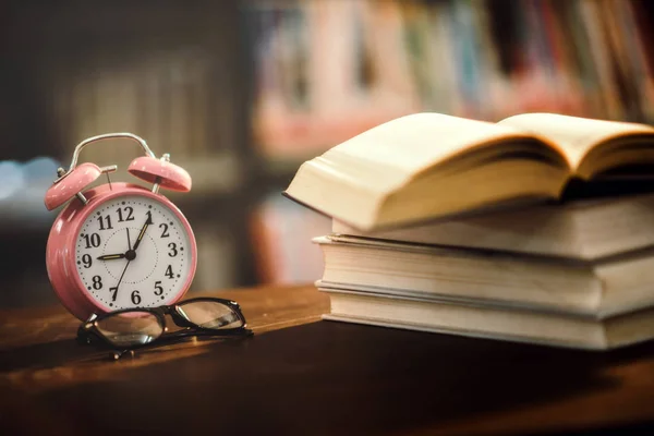 Clock pink and Book in library with open textbook,education lear