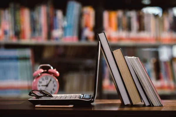 Komputer przenośny i książka, różowy zegar na miejscu pracy w bibliotece Roo — Zdjęcie stockowe