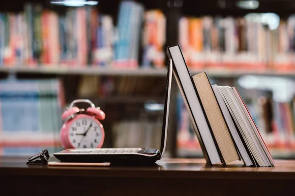 Komputer przenośny i książka, różowy zegar na miejscu pracy w bibliotece Roo — Zdjęcie stockowe