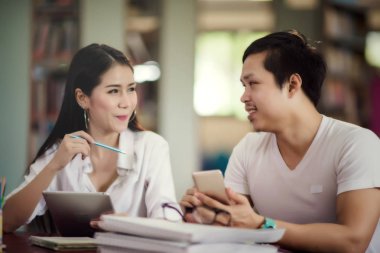  Öğrenen genç öğrenciler, arka planda kütüphane kitaplıkları