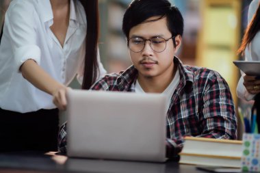  Öğrenen genç öğrenciler, arka planda kütüphane kitaplıkları