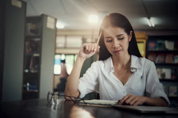 Giovani studenti che imparano, librerie sullo sfondo — Foto Stock