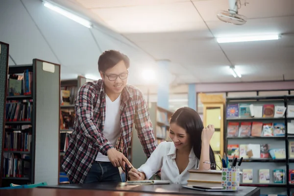 Giovani studenti che imparano, librerie sullo sfondo — Foto Stock