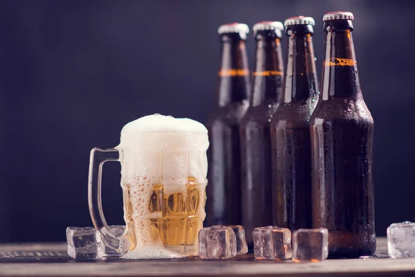 Koyu arka planda cam ve buz ile cam şişe bira