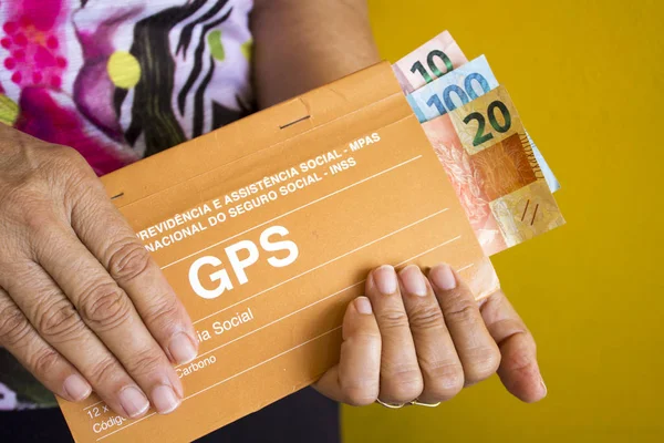 Idosa segurando dinheiro brasileiro para önce sosyal para aposentadoria