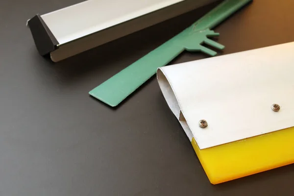 İpek ekran yazdırma metal tekerleği, metal aplikatör ve siyah arka planlı yeşil spatula.