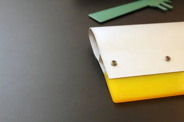 İpek ekran yazdırma metal tekerleği, metal aplikatör ve siyah arka planlı yeşil spatula.