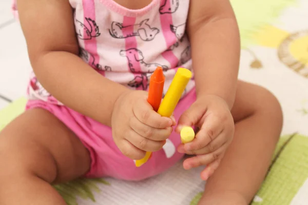 Elinde tebeşir ve kalemle oynayan çocuk