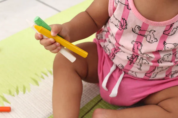 Elinde tebeşir ve kalemle oynayan çocuk