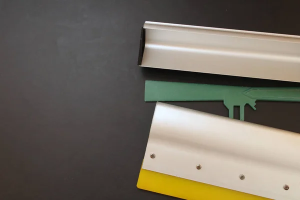 İpek ekran yazdırma metal tekerleği, metal aplikatör ve siyah arka planlı yeşil spatula.