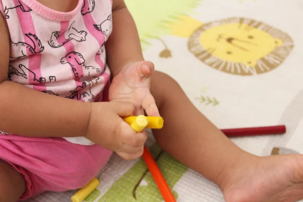 Elinde tebeşir ve kalemle oynayan çocuk