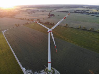 Kırsal alanda gün batımında çayırdaki rüzgar türbinlerinin hava manzarası
