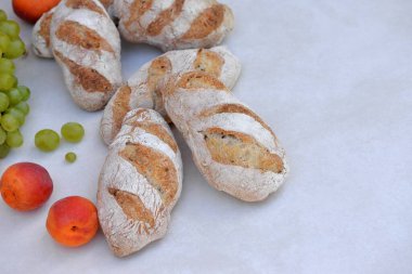 Ev yapımı buğday ekmeği küçük ekmekler / baget çekirdekli ve arka planda meyveli.