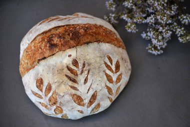 Arka planda otlar ve siyah taş üzerinde taze pişmiş, ekşi ekşi ekmek.; 