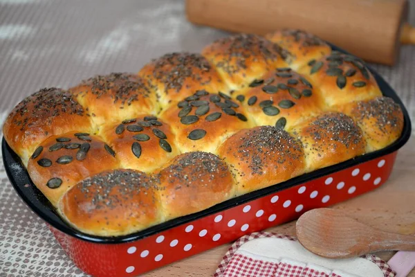 家庭烘焙的软酸性面团小面包 面包卷 面包包 红色烘烤盘 背景为面团辊 — 图库照片