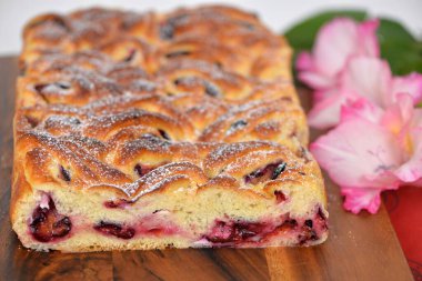 Taze pişmiş maya ruloları / erikle doldurulmuş tatlı brioche hamur örgüsü; dilimlenmiş lezzetli ekmeğin ekmek dokusu. Arkaplanda gladioli