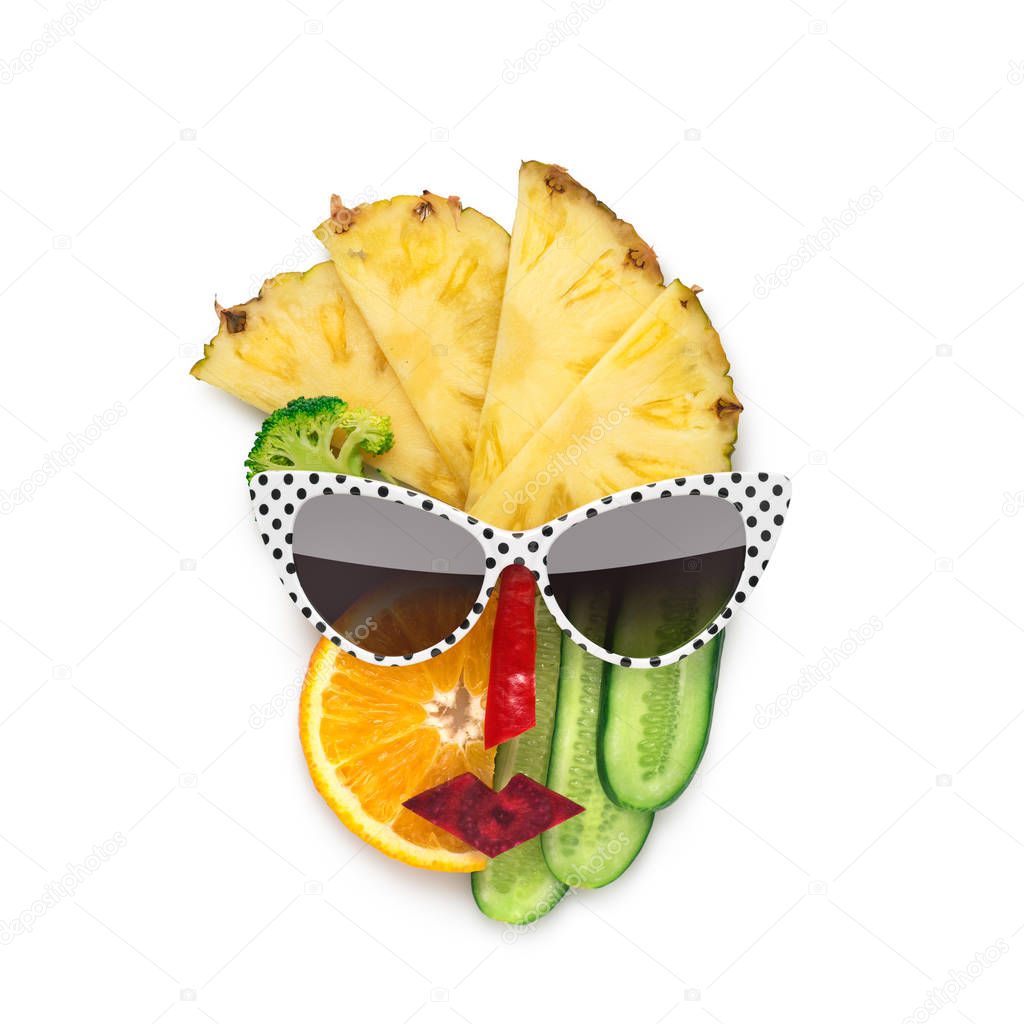 Creative concept photo of cubist style female face in sunglasses made of fruits and vegetables, on white background.