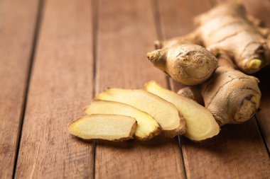 Ahşap zeminde zencefil kökü ve dilimlenmiş.