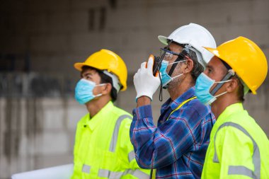 Yakın plan Asyalı mühendis teknisyen işçi müfettişi inşaat alanında çalışma kalitesini kontrol etmek için bir ev inşa etti.
